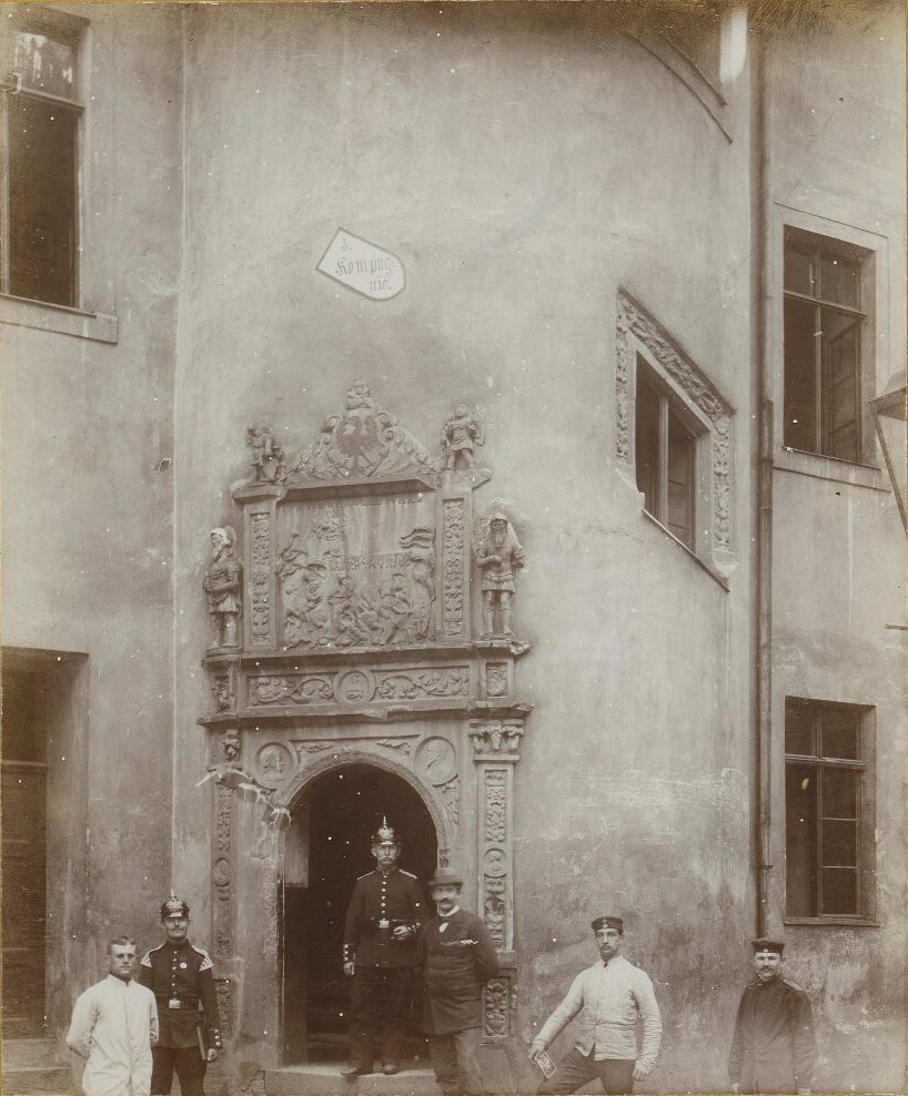 Carved Renaissance portal in the Schloss courtyard, with a sign reading 3. Kompagnie above it and six men posing below, some in uniform.