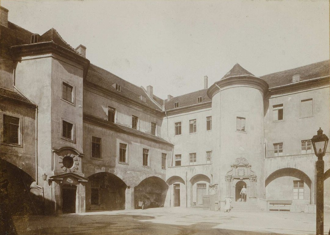 Courtyard of the Schloss: arcades, a round stair tower with a carved portal, a gas lamp in the foreground.
